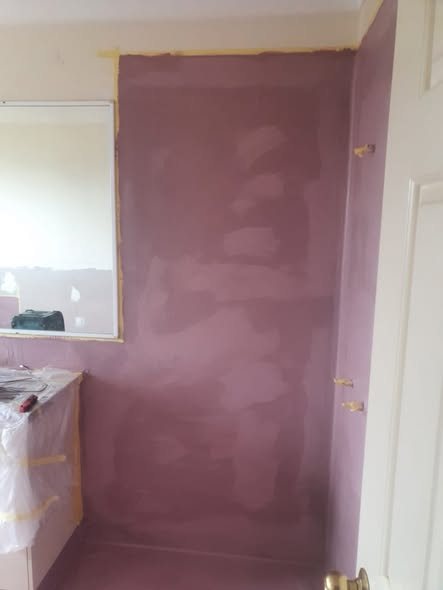 Pink waterproof membrane being rolled onto a wall